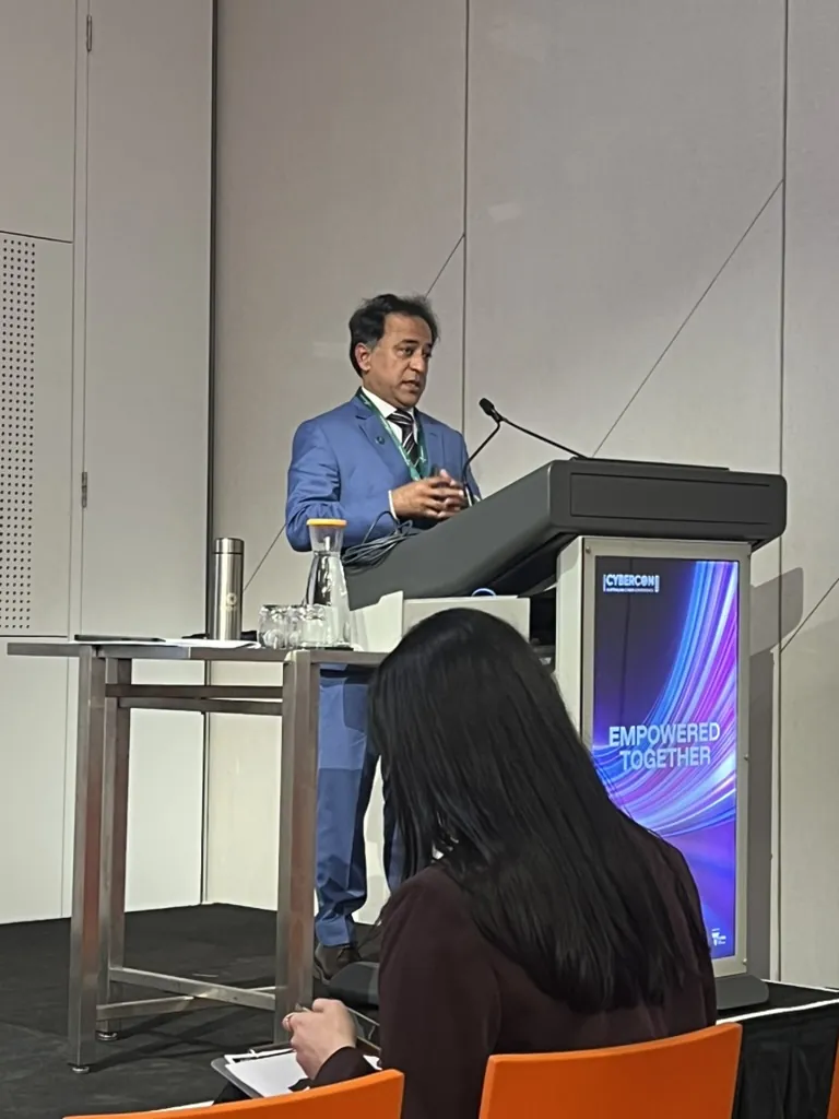 Our founder speaking from the podium at AISA CyberCon 2026, Melbourne Convention and Exhibition Centre