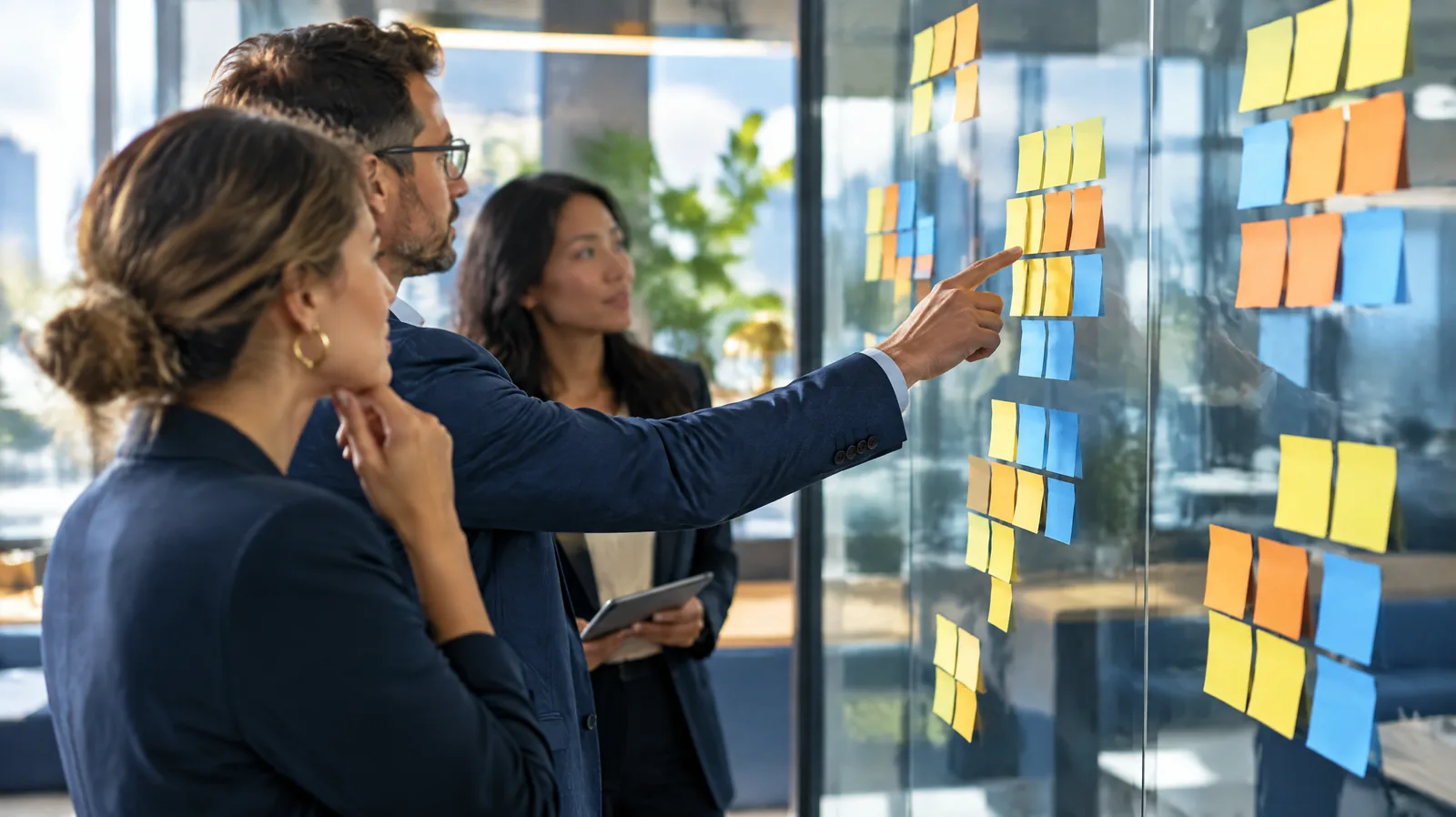 Team at a glass wall clustering sticky notes during a risk assessment workshop, representing ISO 27001 risk assessment
